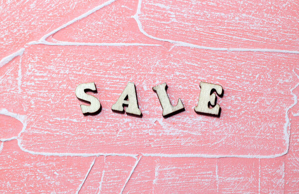 The inscription sale on a pink background. Wooden letters. Business concept. Close-up. Selective focus.