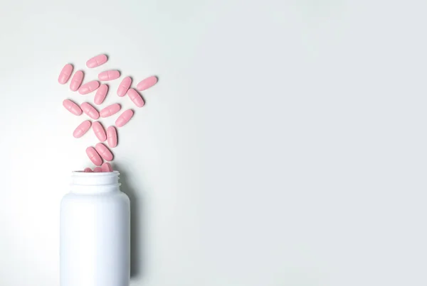 白い瓶の中のピンクの錠剤。白い背景の錠剤 — ストック写真