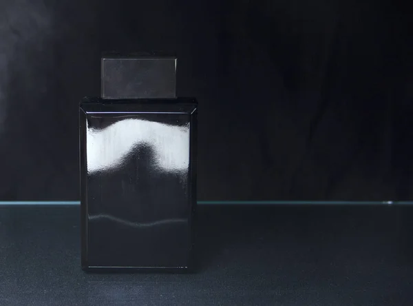 Black bottle of mens perfume on a dark background — Stock Photo, Image
