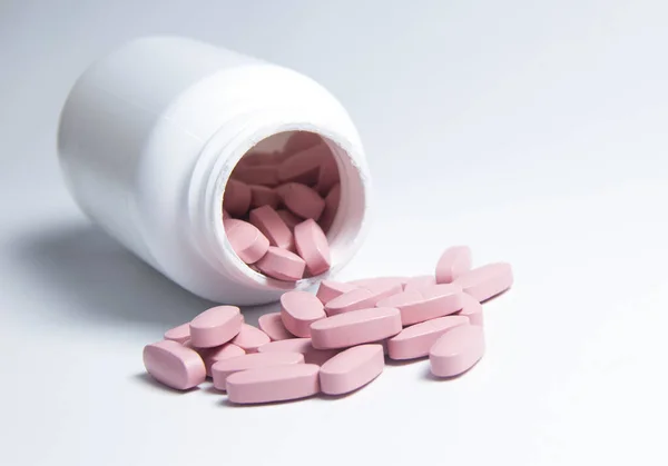 ピンクの錠剤が白い瓶からこぼれた — ストック写真