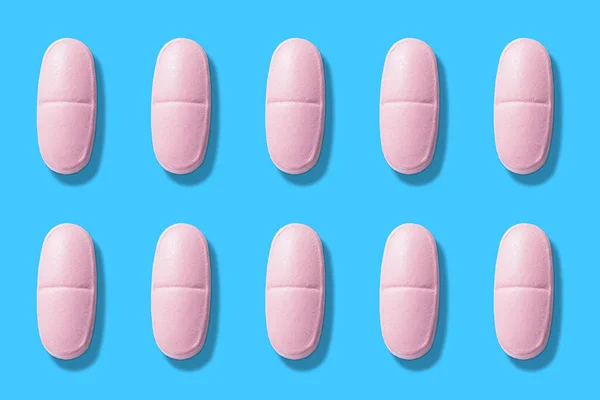 Pastillas rosadas sobre fondo azul. píldoras de color rosa sobre fondo azul vista superior —  Fotos de Stock