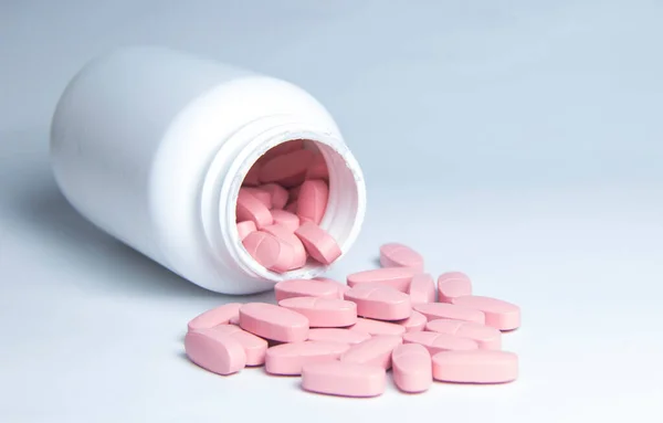 ピンクの錠剤が白い瓶からこぼれた — ストック写真