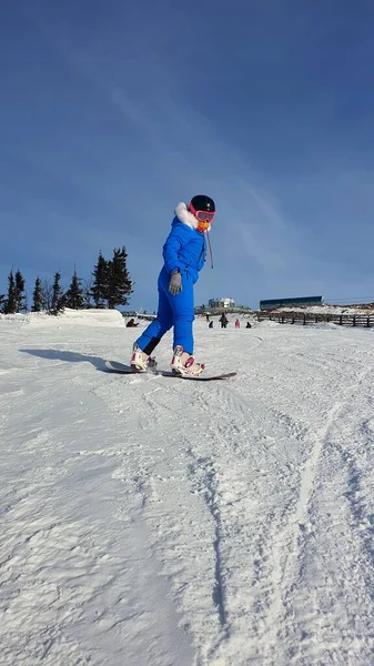 Fiatal lány snowboard. A lány egy gyerek a snowboardon. Függőleges fénykép — Stock Fotó