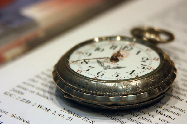 Reloj de bolsillo viejo acostado en el libro con el texto Inglés —  Fotos de Stock