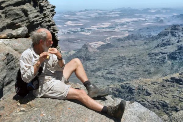 Old man plays flute on top of mountain — Stock Photo, Image