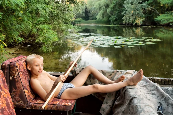 Boy lying in motor boats on river — Stock Photo, Image