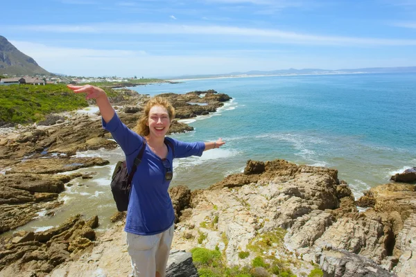 Naurava nainen seisoo jyrkällä kivellä — kuvapankkivalokuva