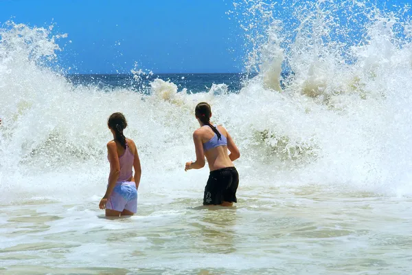 Zwei jugendliche Mädchen stehen vor großen Wellen — Stockfoto