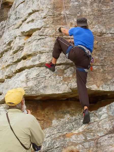 Old coach looks at rock climber — Stock Photo, Image