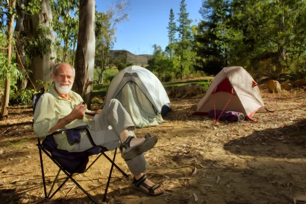 Smiling old hiker in the camp in morning forest — Stock Photo, Image