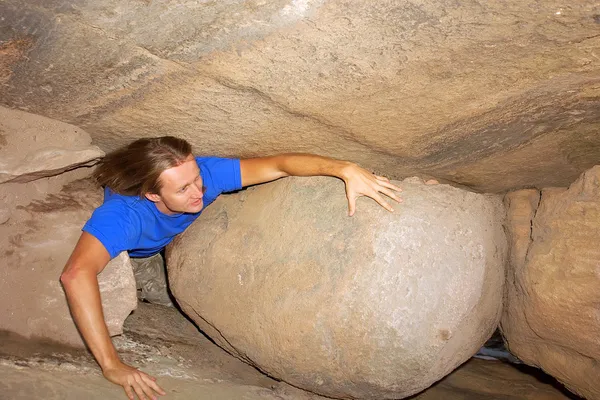 Young man creeps through cave — Stock Photo, Image