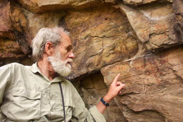 Oude man wijst op de oude bushman schilderijen — Stockfoto