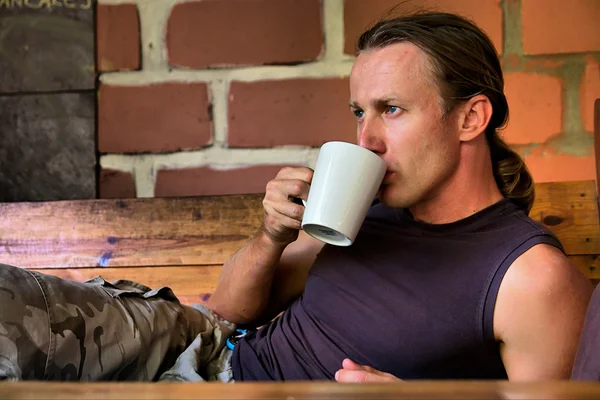 Junger Mann trinkt neben dem Feuer liegenden Kaffee — Stockfoto
