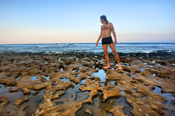 El hombre se para en la playa rocosa — Foto de Stock