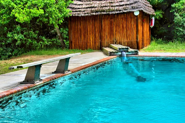 House and bench next to pool — Stock Photo, Image