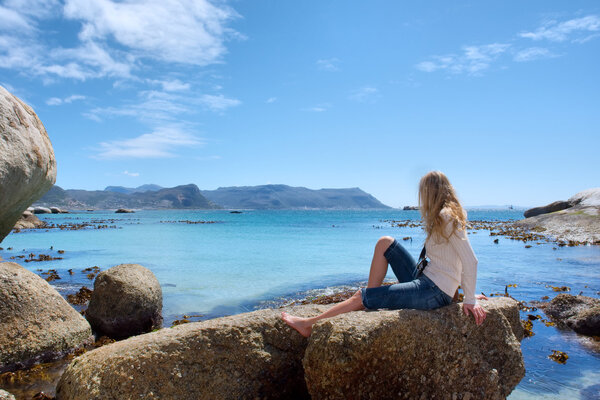 Blonde girl enjoys sun on rocky beach