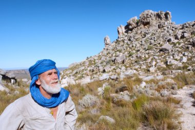 Old man in bedouin clothes looks at mountains clipart