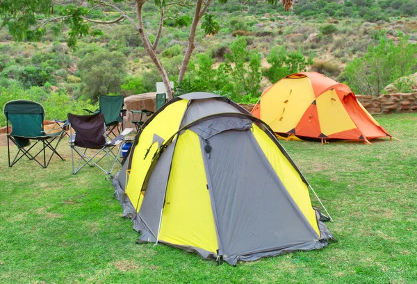 Duas tendas e cadeiras no local de acampamento — Fotografia de Stock