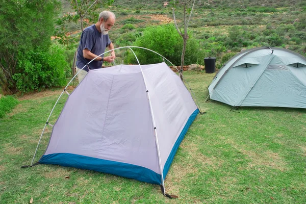 Senior hiker assembles tents on camping site — Stock Photo, Image