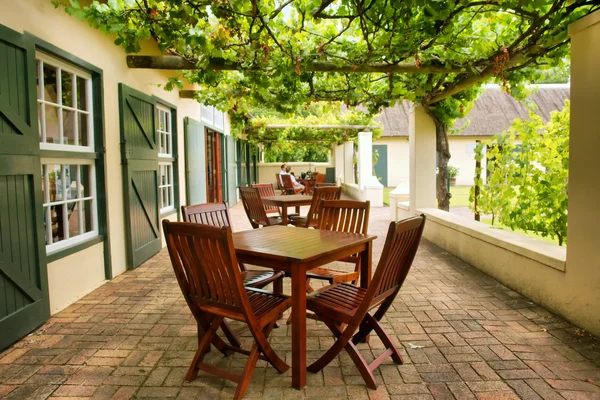 Tische auf der mit Weinreben bedeckten Terrasse — Stockfoto