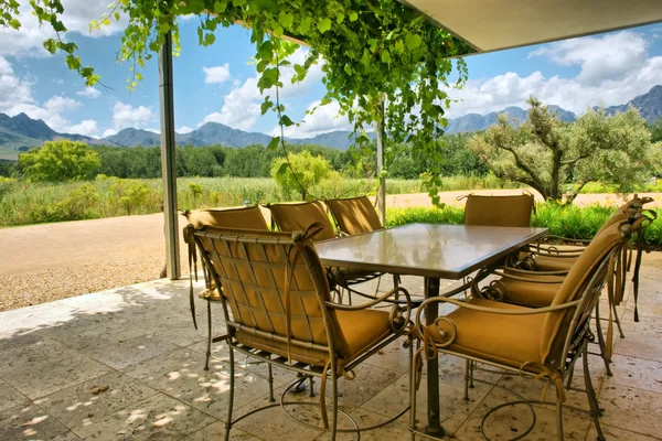 Стол в крытом виноградной лозой павильоне рядом с великолепными горами — стоковое фото