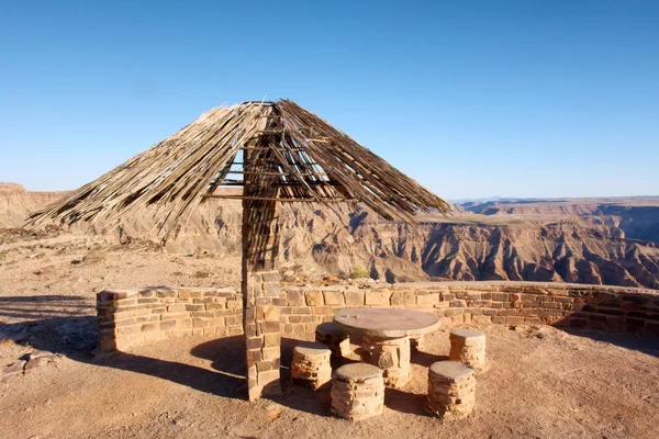 Thatch-roofed umbrella against canyon — Stock Photo, Image