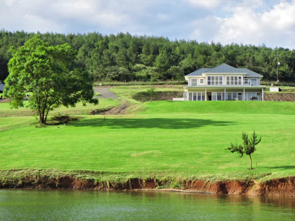 Grande maison avec pelouse à côté du lac — Photo