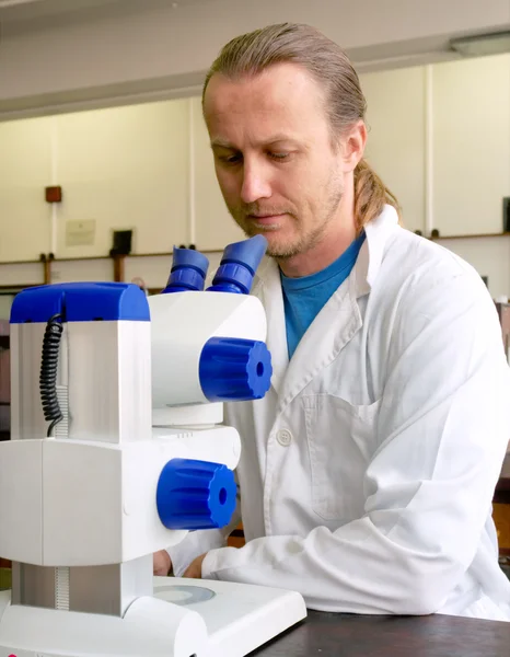 Mannelijke onderzoeker in laboratoriumjas kijkt naar de Microscoop — Stockfoto