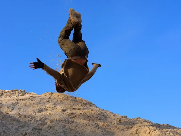 Teenager provádí freerunning kotrmelec na písečném kopci — Stock fotografie