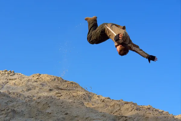Genç kayma atlama kum tepe üzerinde gerçekleştirir. — Stok fotoğraf