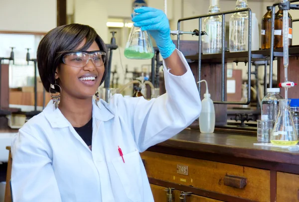 Gelukkig Afrikaanse vrouwelijke onderzoeker met glazen apparatuur — Stockfoto