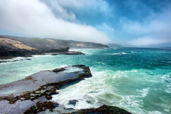 Geweldig uitzicht op de mistige rotsachtige strand — Stockfoto