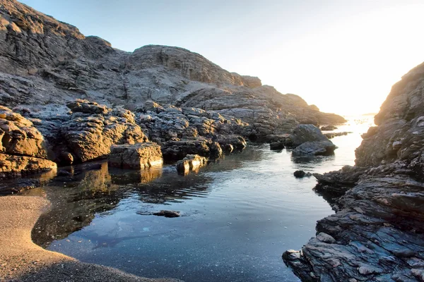 Malé skalnaté pláže v západu slunce světlo — Stock fotografie