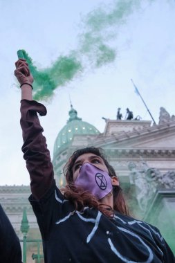 Buenos Aires, Arjantin; 24 Eylül 2021: Küresel İklim Grevi, tek kollu genç eylemci, Ulusal Kongre 'de yeşillik yıkamaya karşı bir gösteri kapsamında yeşil ışık yaktı.