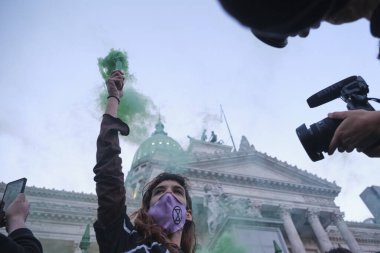Buenos Aires, Arjantin; 24 Eylül 2021: Küresel İklim Grevi, tek kollu genç eylemci, Ulusal Kongre 'de yeşillik yıkamaya karşı bir gösteri kapsamında yeşil ışık yaktı.