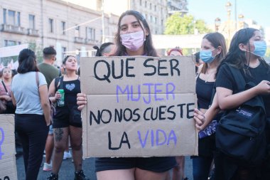 Buenos Aires, Arjantin; 8 Mart 2022: Uluslararası feminist grev, genç bir kadın, kadın olmanın hayatımıza mal olmadığı yazılı bir karton taşıyor.
