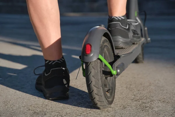 クローズアップ画像は 市内の彼の電動キックスクーターで男の足は晴れた朝 持続可能性 現代性 クリーンエネルギーとグリーンモビリティ エコ輸送の概念 — ストック写真