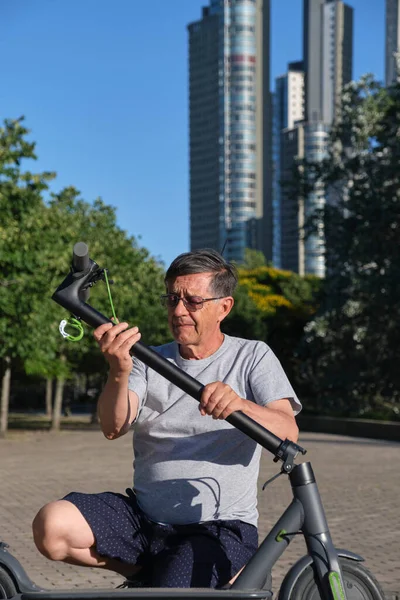 Hispanic Senior Man Vecklar Sin Elektriska Sparkcykel Utomhus Solig Morgon — Stockfoto