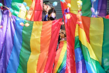 Buenos Aires, Arjantin; 6 Kasım 2021: LGBT Onur Yürüyüşü. Sırtında gökkuşağı bayrağı olan köpek, daha fazla bayrakların arasına bakıyor..