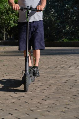 Güneşli bir sabahta şehirde elektrikli scooterıyla tanınmayan bir adam. Aktif kentsel yaşam, modern hareketlilik ve ekolojik ulaşım kavramları.