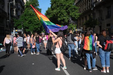 Buenos Aires, Arjantin; 6 Kasım 2021: LGBT Onur Yürüyüşü. Genç bir kadın gökkuşağı bayrağını göndere çekiyor, şehrin şehir merkezinde yürüyor..