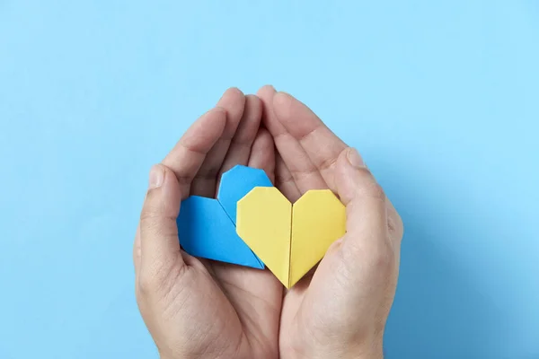 Ręce Nierozpoznawalnej Osoby Trzymającej Chroniącej Parę Niebiesko Żółtych Serc Origami — Zdjęcie stockowe