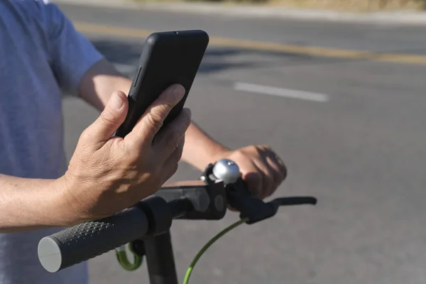 Nierozpoznawalny Mężczyzna Patrzący Swój Smartfon Przed Jazdą Skuterze Elektrycznym Mieście — Zdjęcie stockowe