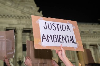 Buenos Aires, Arjantin; 22 Nisan 2022: Dünya Günü boyunca insanlar Ulusal Kongre önünde toplanıyor; çevre adaletinin mesajını taşıyan bir poster asıyorlar..