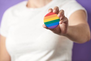 Kameraya gökkuşağı LGBT rozetini gösteren tanınmamış bir kadın. Geylerin, lezbiyenlerin, biseksüellerin ve tranların gururu, cinsel yönelim çeşitliliğine ve cinsiyet kimliğine saygı.