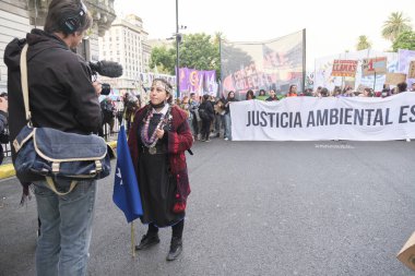 Buenos Aires, Arjantin; 22 Nisan 2022: Dünya Günü gösterisi sırasında Mapuche halk bayrağı taşıyan bir kadınla röportaj yapan adam.
