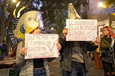 Buenos Aires, Arjantin; 22 Nisan 2022: Dünya Günü. Kafalarında balık kuklaları olan aktivistler. Posterler: Sistem değişikliği istiyoruz, iklim değişikliği değil. Vejetaryenlik iklim değişikliğinin cevabıdır. Vejetaryen.