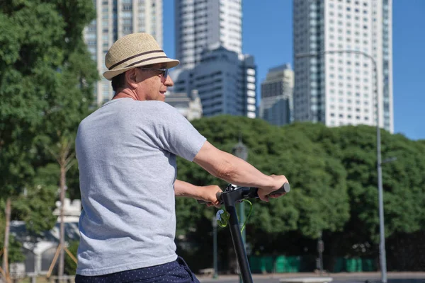 İspanyol son sınıf öğrencisi yazın şehirde elektrikli scooterıyla geziyor. Sürdürülebilirlik kavramları, yaz turizmi, aktif yaşam, temiz enerji ve yeşil hareketlilik, ekolojik ulaşım.