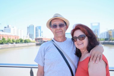 Portrait of a senior Hispanic tourist couple in Puerto Madero, a trendy neighborhood in Buenos Aires, Argentina. Concepts: traveling and enjoying the outdoors, active retirement.