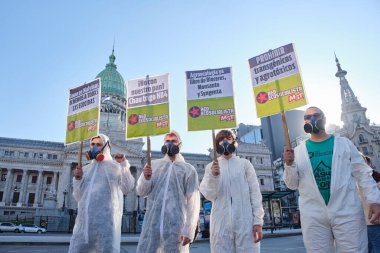 Buenos Aires, Arjantin; 21 Mayıs 2022: maskeli ve biyo-tehlike giysileri giyen bir grup aktivist, ulusal kongre önünde tarımda GDO ve böcek ilacı kullanımına karşı işaretler taşıyor..